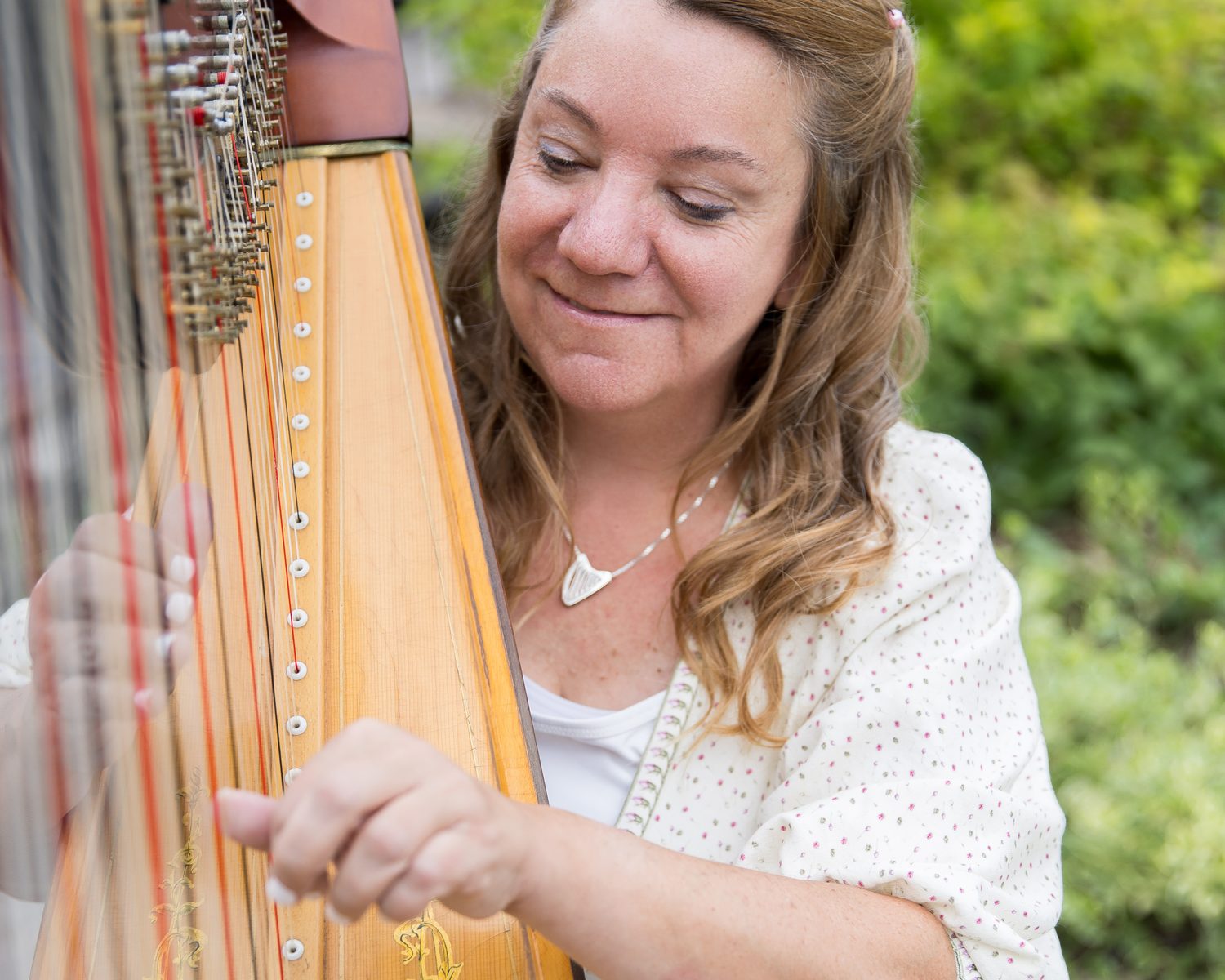 Patricia Turse playing her pedal harp in a garden